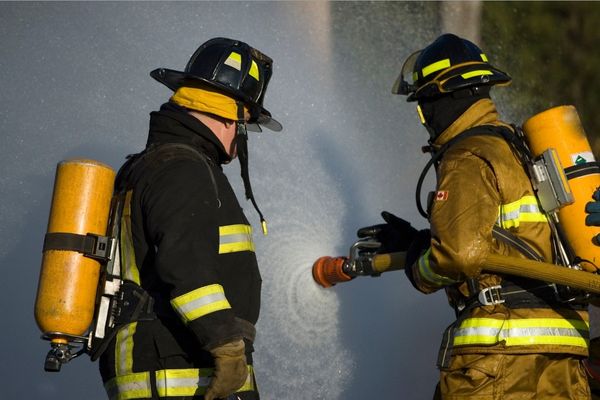 firefighter spraying water on house fire